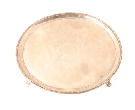 A GEORGE III SILVER CIRCULAR SALVER by Robert Jones I, London 1778, with bead rim on four panel feet, period engraved shield 