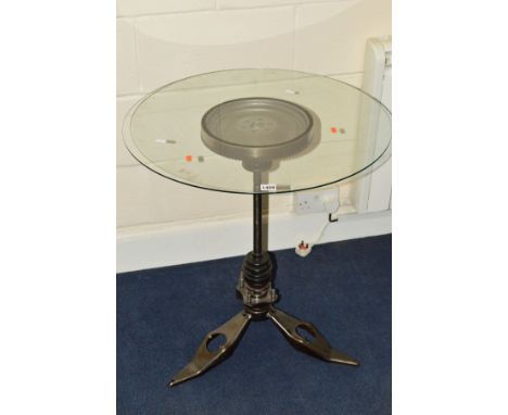 AN INDUSTRIAL CIRCULAR GLASS TOPPED TABLE, on base formed from engine parts, diameter 64cm x height 71.5cm