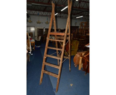 A WIDE WOODEN STEP LADDER, with casters to one side