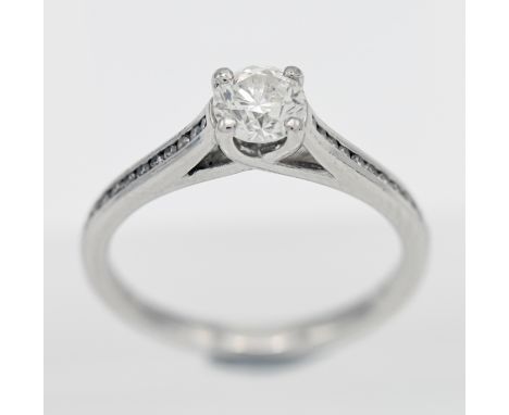 A platinum diamond solitaire ring with channel set shoulders, set with one round brilliant cut diamond total 0.46ct, assessed