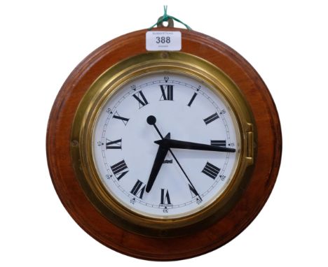 A brass-cased ship's bulkhead clock by Sestrel, mounted on a teak circular panel, the brass case engraved to Lt.J.Dusty Mille