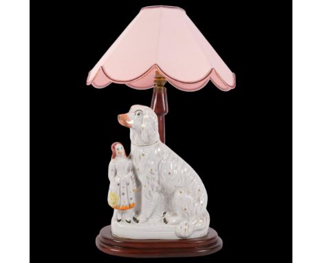 A table lamp with pink shade, supported by a Staffordshire Spaniel and figure, H56cm
