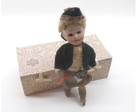 An early 20th Century Goebel Bisque Head Boy Doll dressed in Scottish costume, (missing lower limbs) 