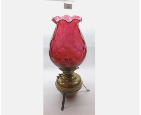 A late 19th/early 20th Century Oil Lamp with cranberry shade over brass font, raised on a base metal stand, 20 1/2" high   40