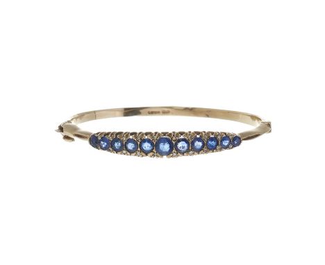 A 9ct gold graduated sapphire hinged bangle bracelet, with rose-cut diamond double spacers, total estimated sapphire weight 2