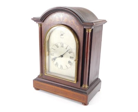 An Edwardian mahogany table clock, in arched case, the 12cm wide silvered etched Roman Numeric dial flanked by cylindrical co