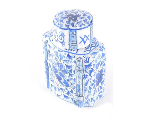 A 19thC Dutch Delft pottery tea caddy, of shouldered form with removable lid, profusely decorated with flowers on a shaped ba