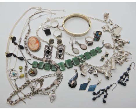 A silver charm necklace hung with many silver and white metal charms, a white metal plique a jour enamel ring and other items