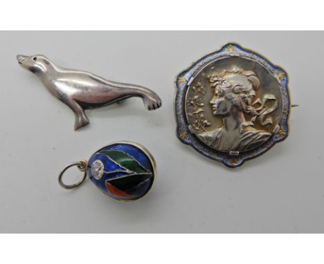 A white metal and enamel Art Nouveau brooch, a silver Ola Gorie seal brooch and a white metal enamelled egg pendant set with 
