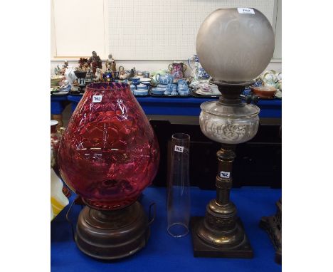 A copper paraffin lamp with large cranberry glass shade, 49cm high overall and another paraffin lamp with Art Nouveau style d