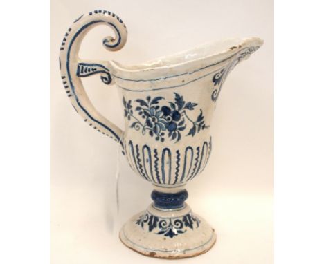 An 18th Century French tin glazed jug with blue and white floral decoration and scrolling handle, 26cm high Condition Report: