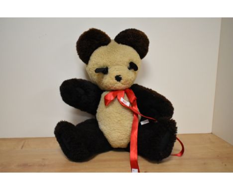 An early 20th century panda teddy bear, having a red bow-tie, glass eyes, swivel legs and arms, h40cm.