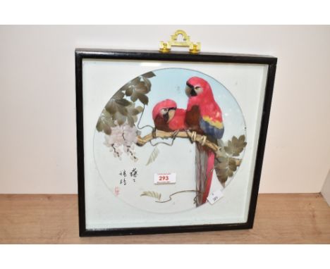 A vintage Chinese picture depicting two tropical parrots hand crafted with feathers, glazed behing a black ebonised frame, st