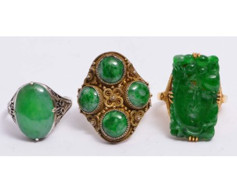 A CHINESE YELLOW METAL RING with rectangular carved jade setting, a Chinese white metal ring with stylised jade setting and a