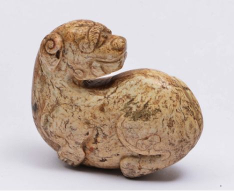 A CHINESE SHANG STYLE BURNT JADE PEBBLE carved as a seated mythical beast with head turned over left shoulder, Tang or later,