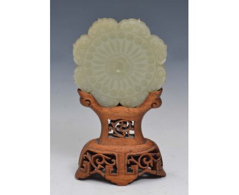A CHINESE PALE CELADON JADE MEDALLION FORM PLAQUE with a 'C' scroll border around a flower head pattern, reverse floral petal