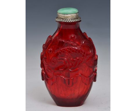 A CHINESE OVOID FORM RED GLASS SNUFF BOTTLE, carved in relief with two fish above a large lotus leaf, with jade stopper, 7.3c