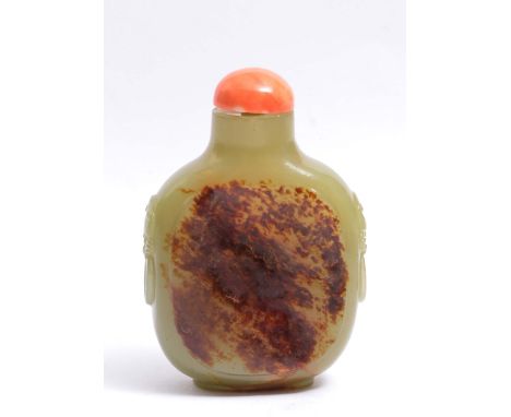A CHINESE FLATTENED OVIFORM SNUFF BOTTLE in pale green jade with irregular mottled brown inclusions, sides with mask mock han