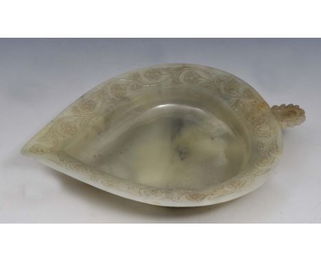 A MUGHAL JADE IN THE FORM OF A LEAF, the rim carved in relief with continuous flowering blooms with scrolling foliage, having