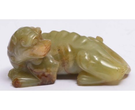 A CHINESE BROWN AND GREEN JADE MYTHICAL BEAST carved in recumbent pose with head turned to look over its left shoulder, Ming,