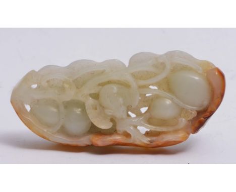 A CHINESE WHITE AND BROWN JADE PENDANT pierced and carved with fruiting gourd plants and other fruits, with foliage and a bat