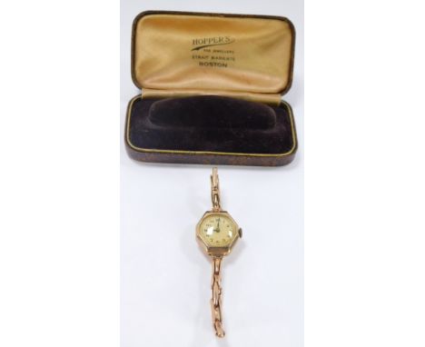 A 9ct gold wristwatch, with an octagonal top with white numeric ceramic dial and blue hands, on an expanding strap, stamped 9