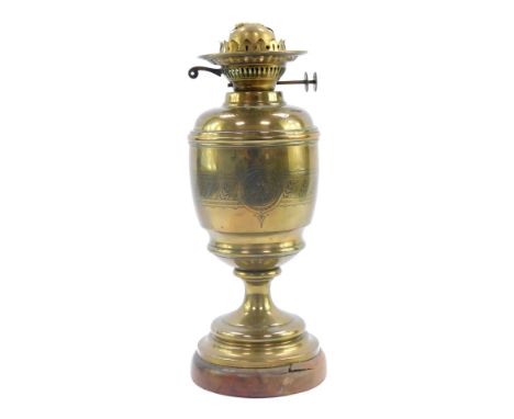 An early 20thC duplex brass oil lamp, with engraved decoration, raised on a wooden base, no chimney or shade, 58cm high.