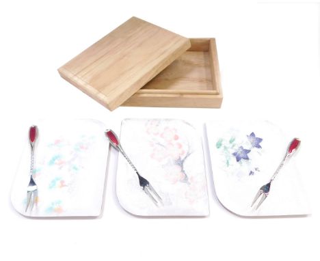 A cased condiment set, with three floral Oriental enamelled serving plates, with three pickle forks, each with red enamel top