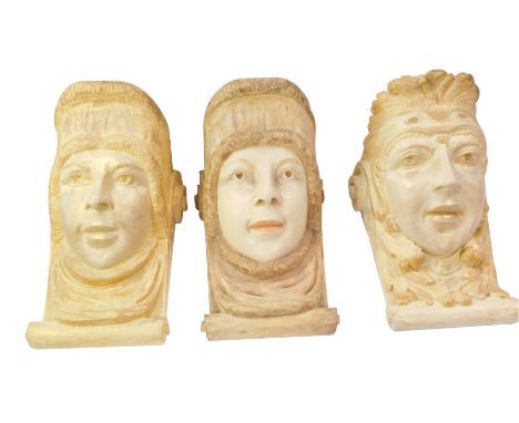 Three plaster wall brackets, each formed as a face with flattened shelf top, 35cm high. (3)