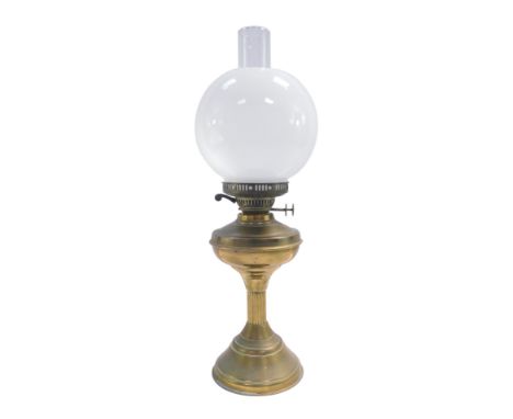 An early 20thC brass oil lamp, with chimney and white glass shade, 57cm high.