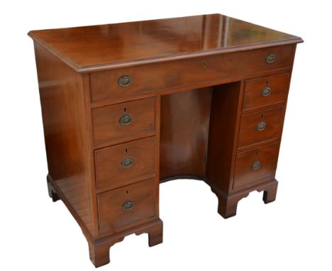 A George III mahogany kneehole desk, with seven drawers each with ring handles, cupboard to kneehole, raised upon bracket fee