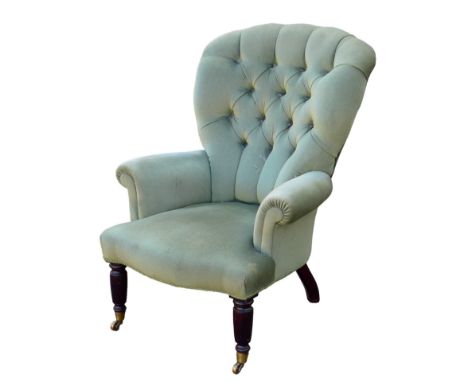 An Edwardian button back armchair, with green velvet upholstery, turned front legs and brass castors, 86 by 66 by 89cm high. 