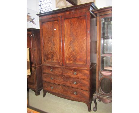 An early 19th century mahogany linen press with moulded and dentil cornice over a pair of rectangular flame veneered panelled