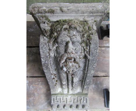 A weathered composition stone corbel/water feature with well defined face mask, Greek key and floral detail, 55 cm in height 