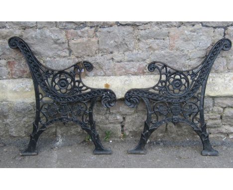 A pair of reproduction cast iron bench ends with decorative pierced foliate detail 