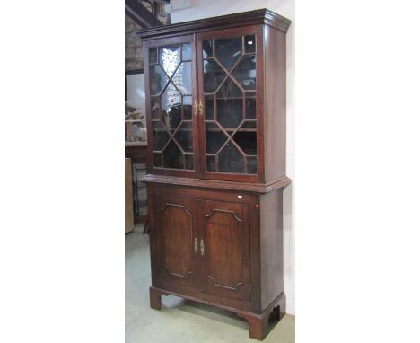 A Georgian mahogany side cabinet in two sections, the upper enclosed by a pair of astragal glazed panelled doors with shelved