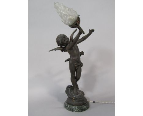 A French cast spelter figural table light of cupid holding a flaming torch, upon a stepped circular marble base, 61cm high 