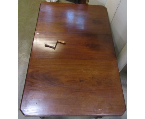 An Edwardian mahogany wind-out extending dining table of rectangular form with canted corners, moulded outline and single add