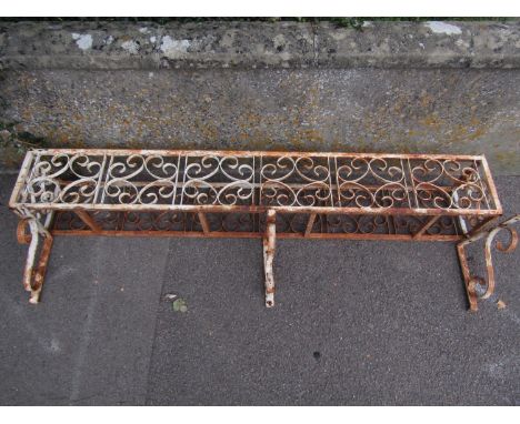 A weathered iron work wall mounted planter/window box of rectangular form with repeating simple scroll work panels and three 