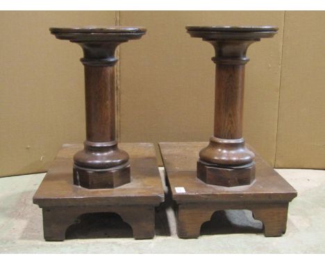 A pair of low oak ecclesiastical stands with turned columns raised on platforms with bracket feet 