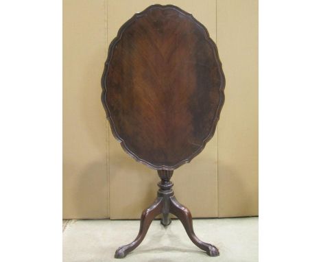 A small Georgian style oval snap top occasional table with pie crust border raised on a turned pillar and tripod with claw an