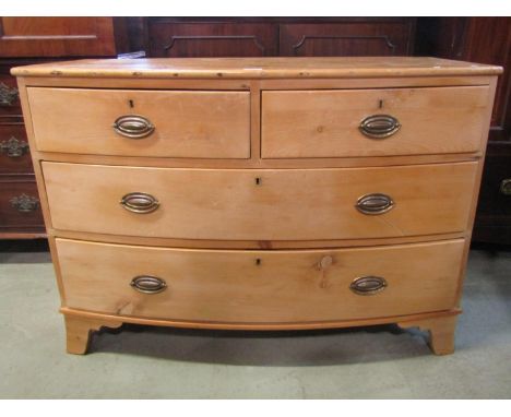 A 19th century stripped pine bow front low bedroom chest of two short over two long graduated drawers, raised on shaped brack