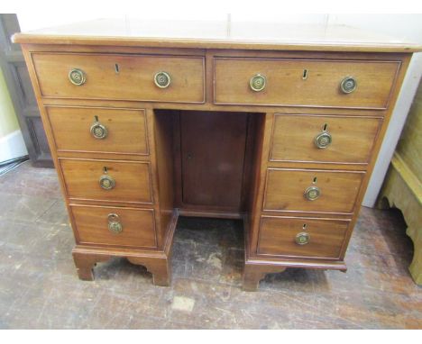 A Georgian mahogany kneehole dressing table fitted with an arrangement of eight drawers and recessed cupboard set on bracket 