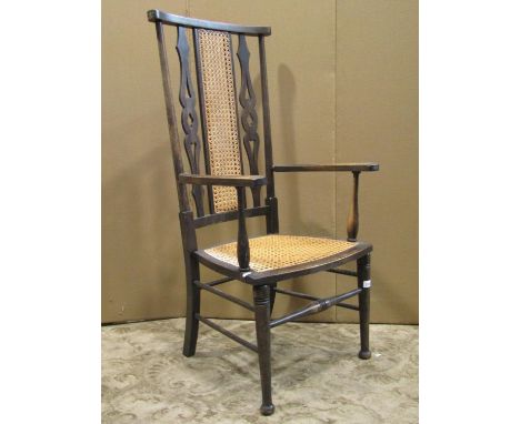 An Edwardian stained beechwood high back, open light weight elbow chair, with cane panelled seat and slender back panel flank
