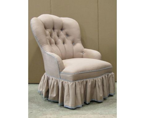 A Victorian drawing room chair with shaped and button back, upholstered finish and turned forelegs with brass caps and brown 