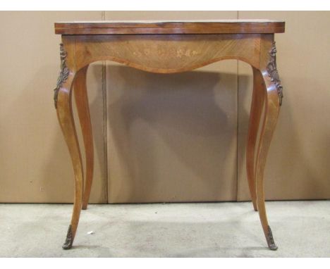 A floral marquetery inlaid fold over top card table with serpentine outline and well matched veneers raised on shaped and swe