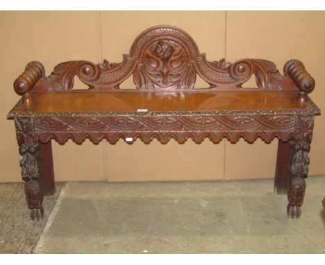 A late Victorian/Edwardian oak low hall bench of rectangular form with turned bobbin arms, carved scrolling acanthus, trailin