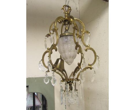 A cast gilt metal hanging ceiling light with open c scroll acanthus frame surrounding a moulded glass shade and faceted dropl