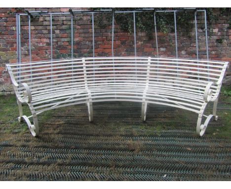 A good quality sprung steel and strap work cream painted garden bench of unusual curved form with open scrolled arms and supp