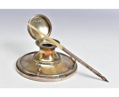 AN EDWARDIAN SILVER CAPSTAN INKWELL FITTED WITH A PEN REST, the hinged cover over a clear glass liner, the stepped base fitte